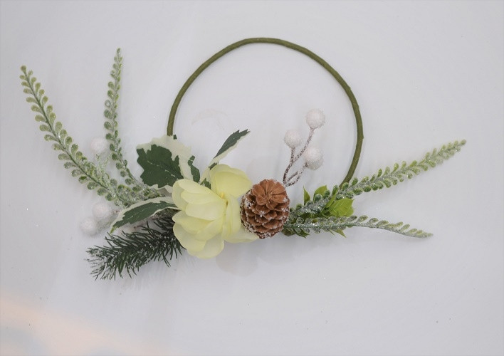 22081 -  Beautiful Cream flower in a wintery wreath with a display of snowy pine needles, cones, berries and green leaves. Floral decoration.  Size   Approx 24cm dia